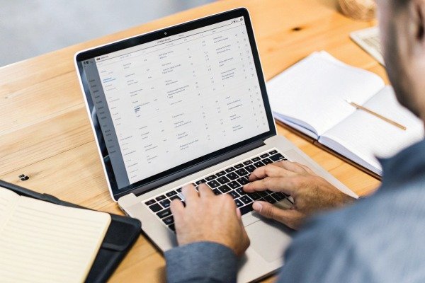 Close up of hands typing on a laptop displaying a data spreadsheet (ID#3)