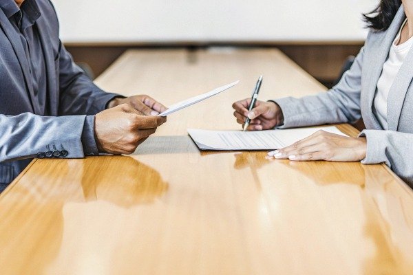 Business partners signing a contract on a wooden office table (ID#4)