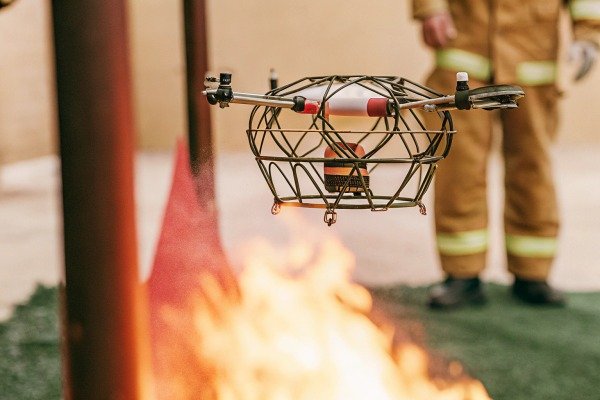 Specialized fire-resistant drone with protective cage flying over an open flame during testing (ID#3)