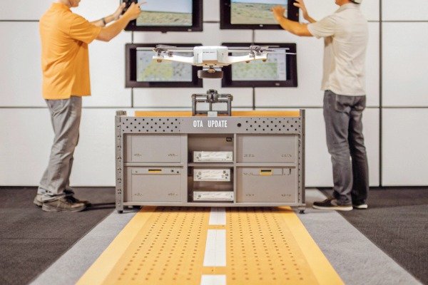 Engineers performing an over-the-air firmware update on a drone at a specialized station (ID#4)
