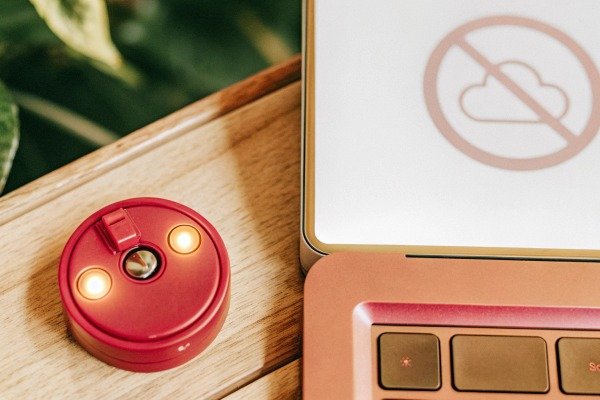 Close up of a red electronic device with glowing lights next to a laptop (ID#3)