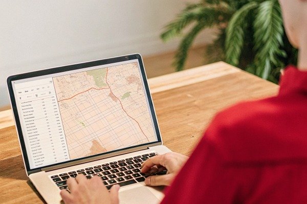 Person using a laptop to view a detailed digital map with navigation data points (ID#4)