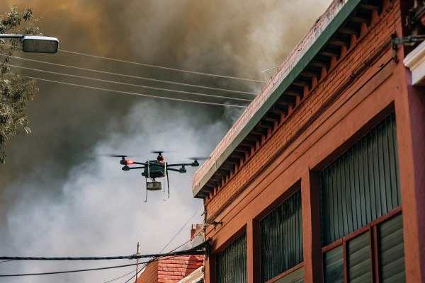Industrial drone flying near a building with thick smoke for emergency monitoring (ID#4)