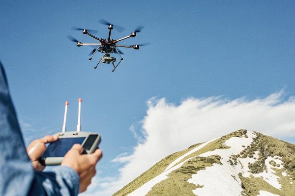 Remote controller screen showing a hexacopter drone flying above a snowy mountain (ID#4)