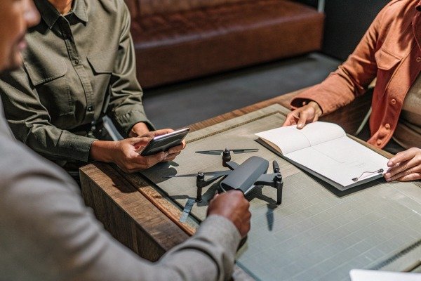 People discussing drone on table indoors (ID#2)