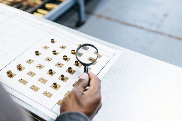 Close up of technician inspecting small electronic drone components using a magnifying glass (ID#2)