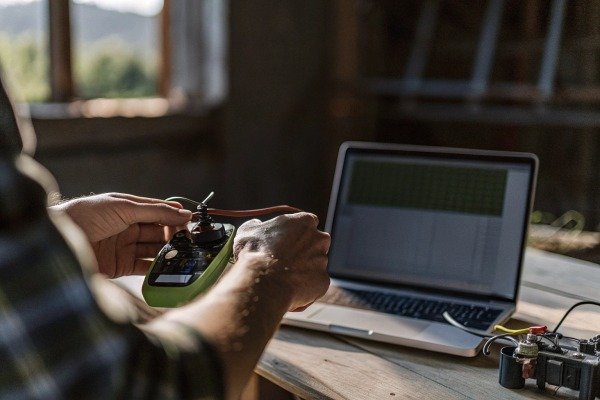 Engineer calibrating drone hardware components while using a laptop in a workshop (ID#3)