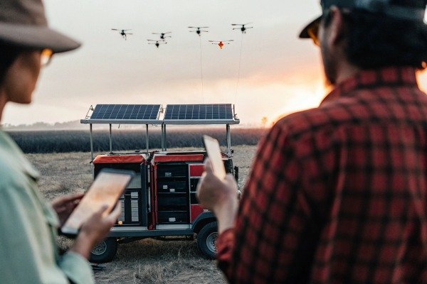 Operators using tablets to control a swarm of drones near a solar power station (ID#3)