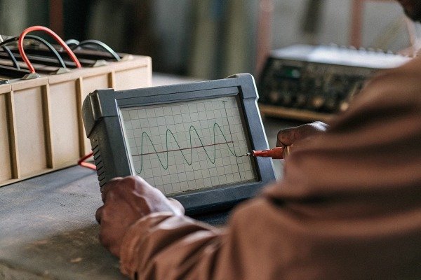 Close up of a technician using an oscilloscope to measure electrical sine wave signals (ID#4)