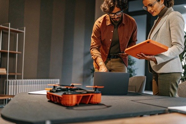 Two engineers discussing drone data using a laptop and tablet in a modern office (ID#5)