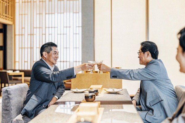 Two businessmen in suits clinking glasses during a formal dinner meeting (ID#2)