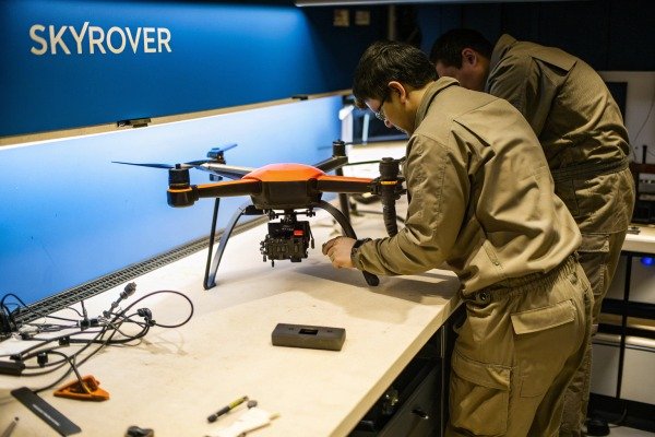 Technicians in a workshop performing maintenance on a large industrial drone (ID#4)