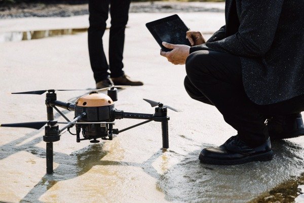 Operator using a tablet to control a professional drone on the ground (ID#2)